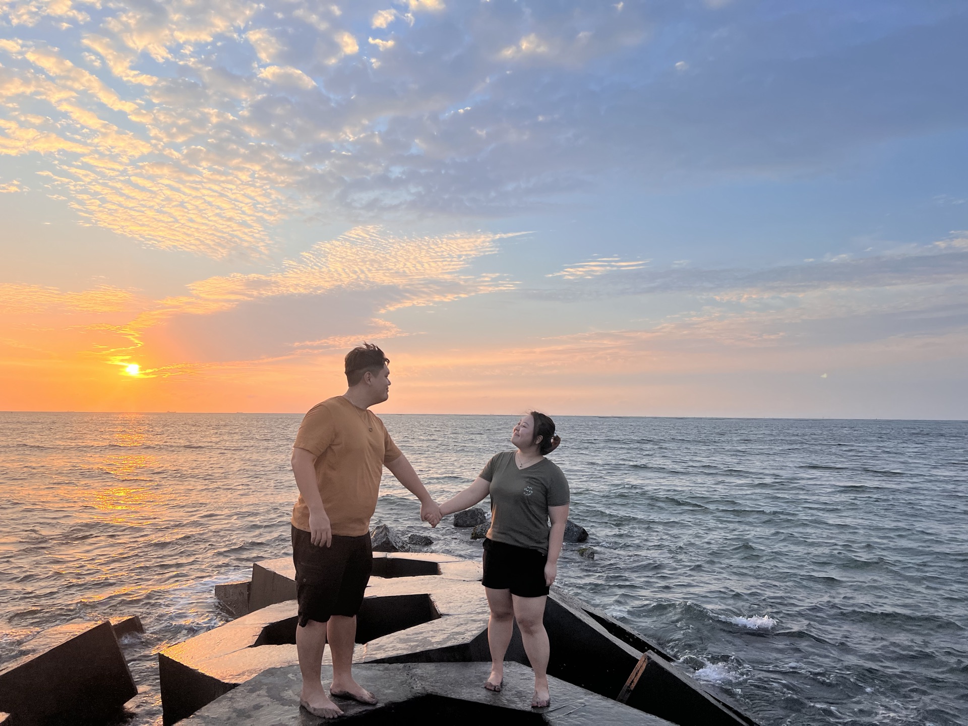 夕陽下，我們牽著手站在海邊消波塊上