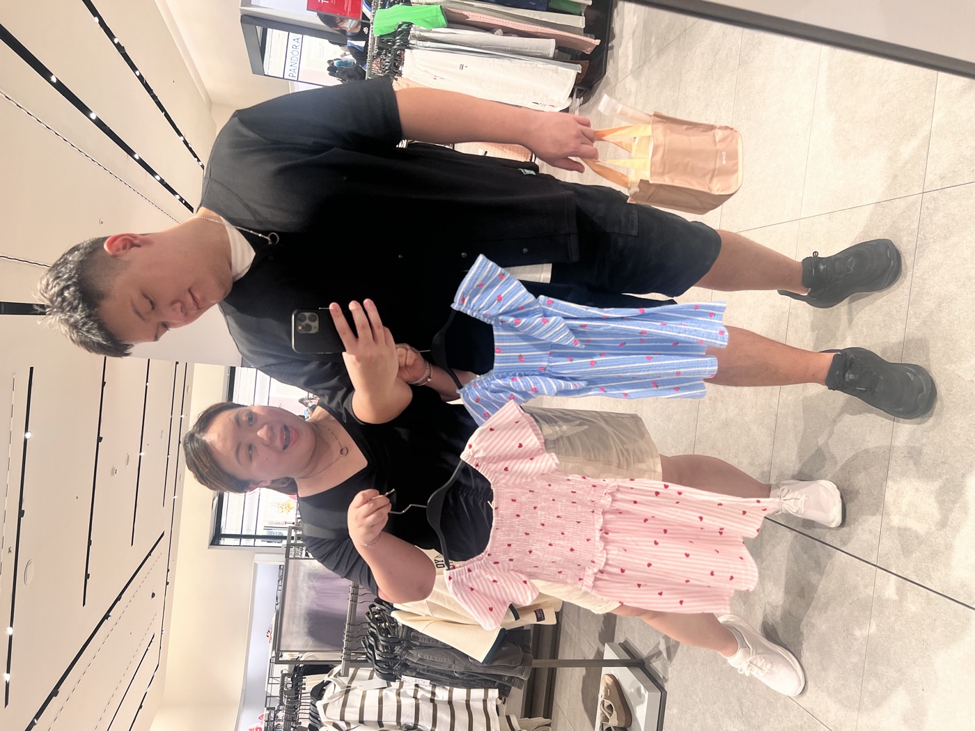 我們在店裡拿著兩件可愛的小孩衣服照鏡子
